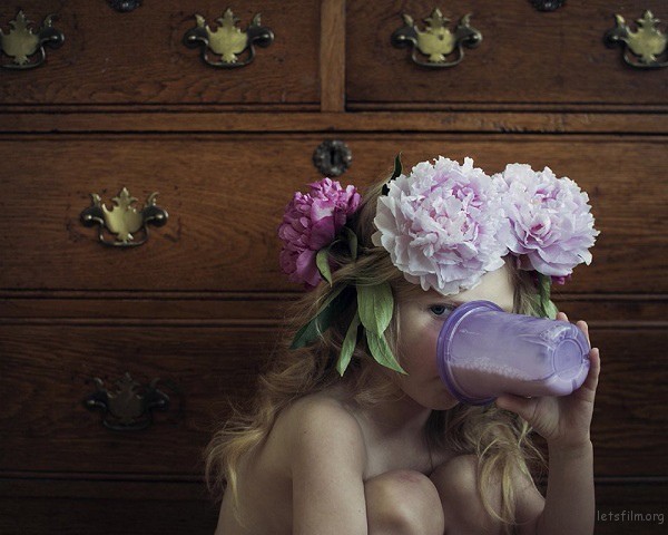 young girl with flowers in her hair drinking milk from a sippy cup