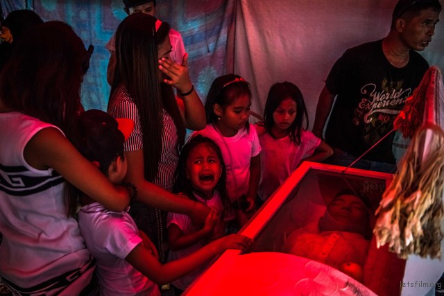 Jimji, 6, cries out in anguish, saying "Papa" as workers move the body of her father, Jimboy Bolasa, 25, for burial, in Manila, Philippines.